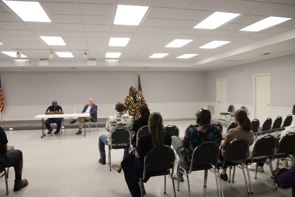 community members particpate in event at community center, engaging in conversation and shaking hands