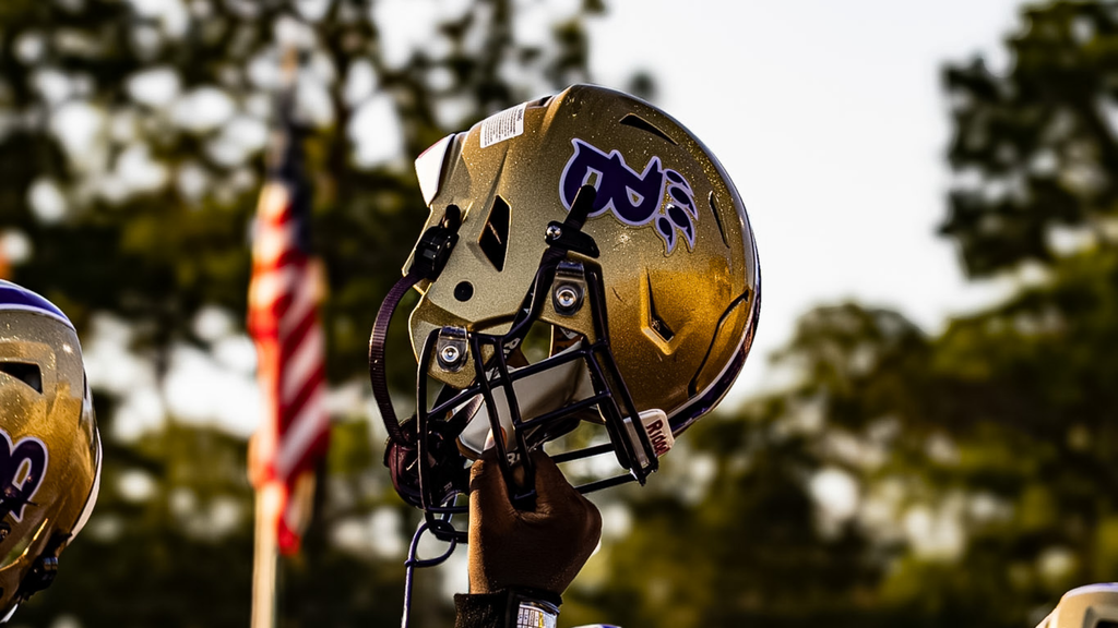 bearcat helmet being held in the air with an american flag in the backgorund
