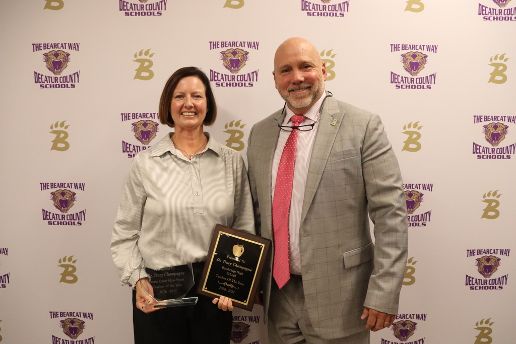 Two Decatur County Schools educators pose with Teacher of the Year awards in front of a Bearcat backdrop.