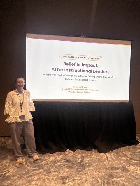 Woman standing beside a presentation screen displaying “Believe to Impact: AI for Instructional Leaders” at the Fall GACIS 2026 Breakout Session.