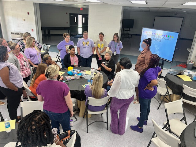 A group of teachers gathers around a table during a math professional development session.