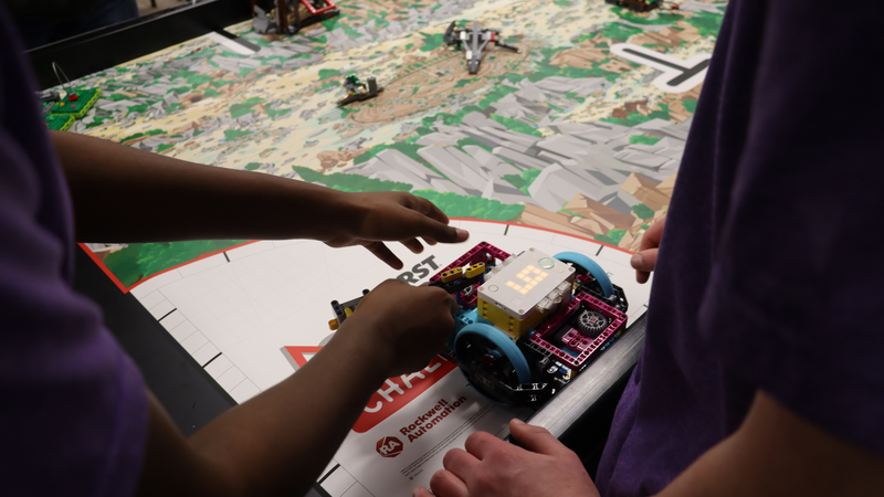 BMS robotics students stand with their innovation project display and prototype.