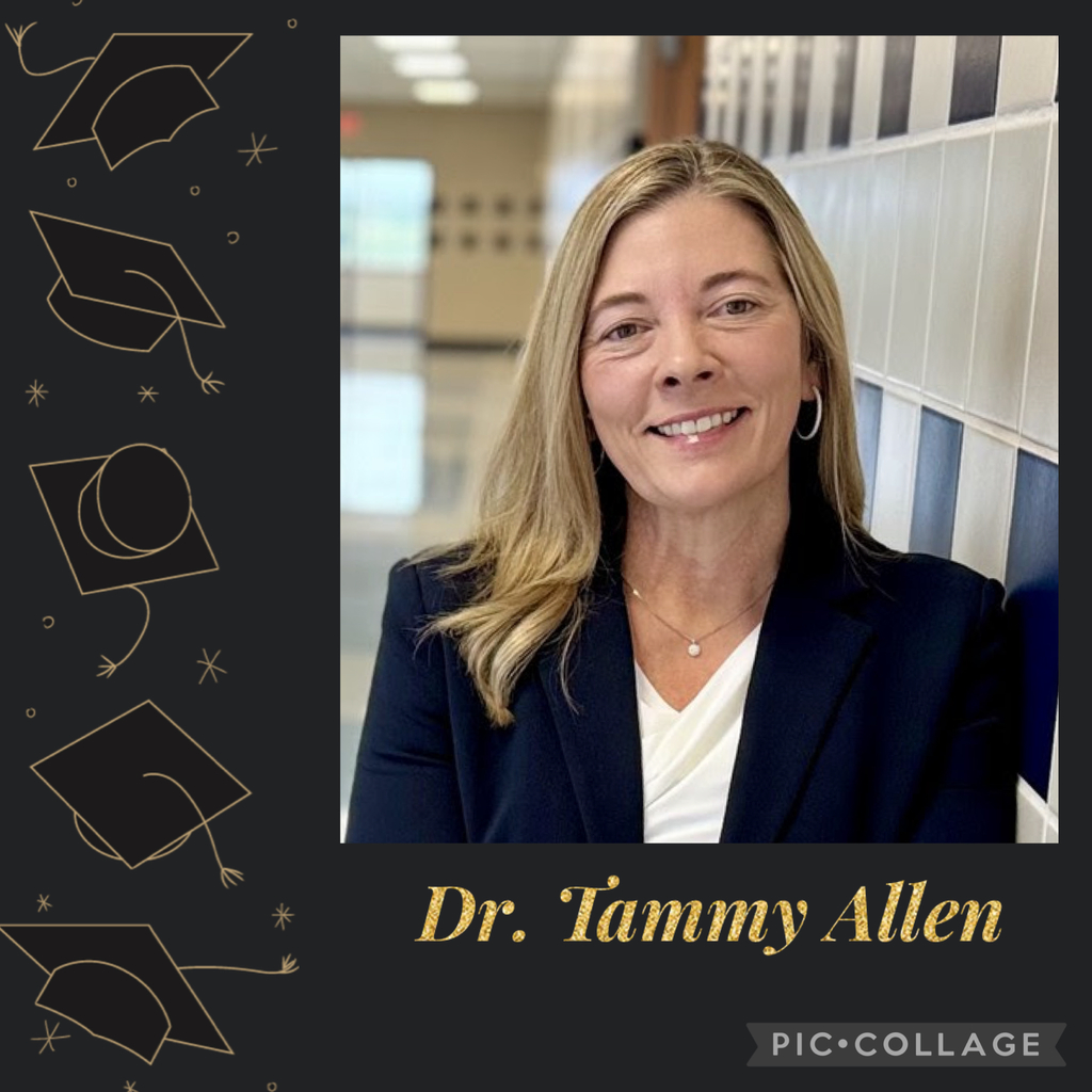 An image featuring a portrait of Dr. Tammy Allen, framed in a celebratory graduation-themed collage.  Subject: A smiling woman with blonde hair, wearing a dark navy blazer, a white blouse, and a simple necklace.  Text: Below the photo, the name "Dr. Tammy Allen" is written in a stylized, gold glitter cursive font.  Background: The left side of the image has a dark background decorated with gold line-art illustrations of graduation caps and stars.  Details: The woman is posing in a hallway with a blue and white tiled wall. A "PIC·COLLAGE" watermark is visible in the bottom right corner.