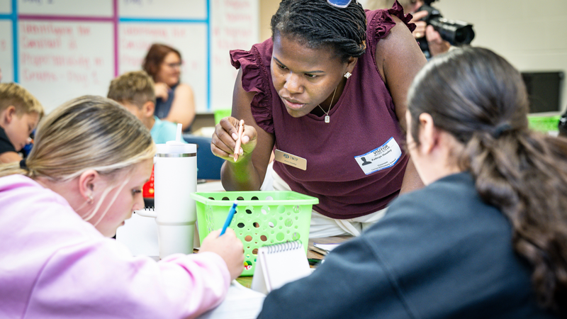 Photo of Katie Hawley talking to students as they solve math problems 