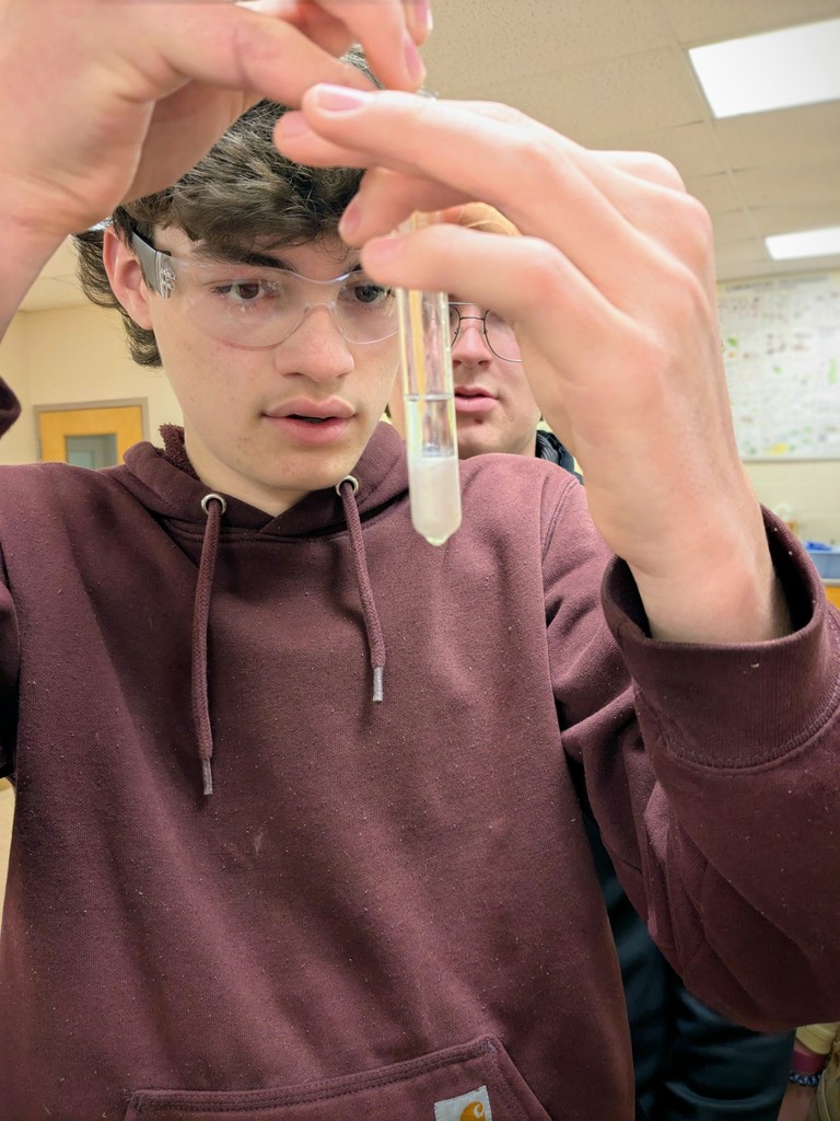 a student holding a test tube and spooling DNA