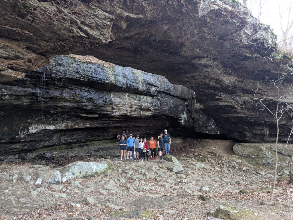 a group of students under a natural bridge