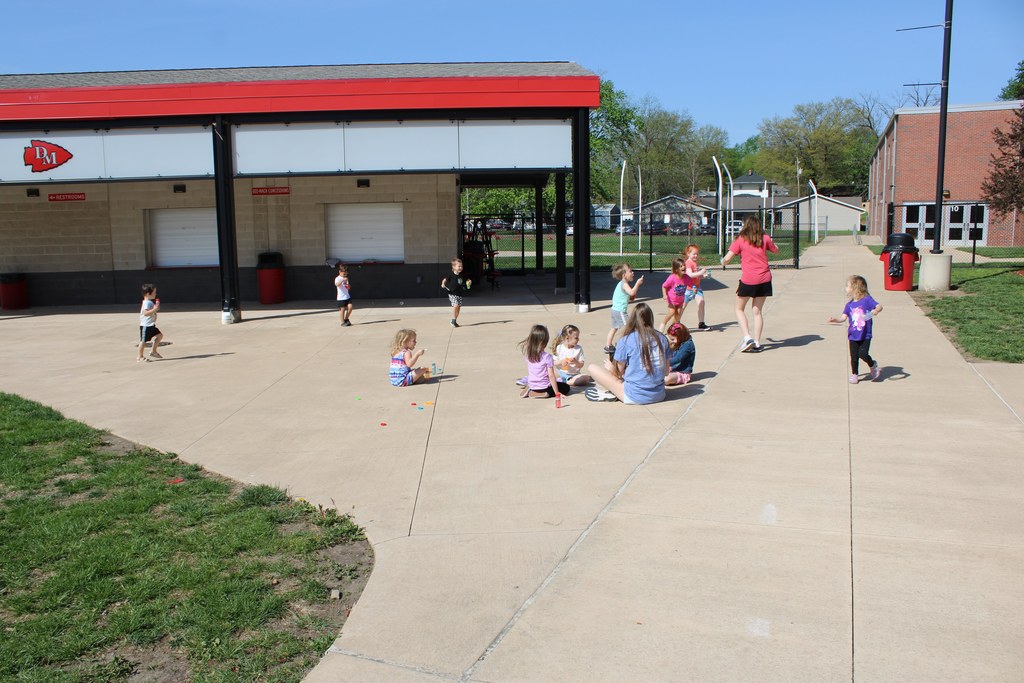High school and preschool students playing outside