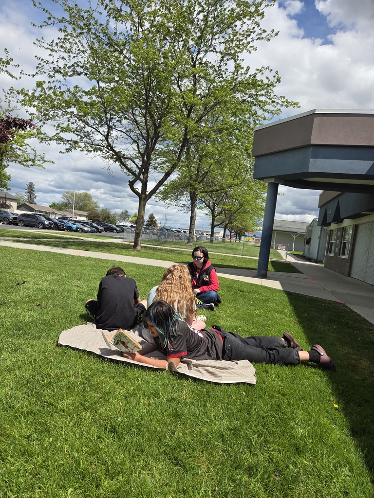 Students taking a testing break in the grass outside school.