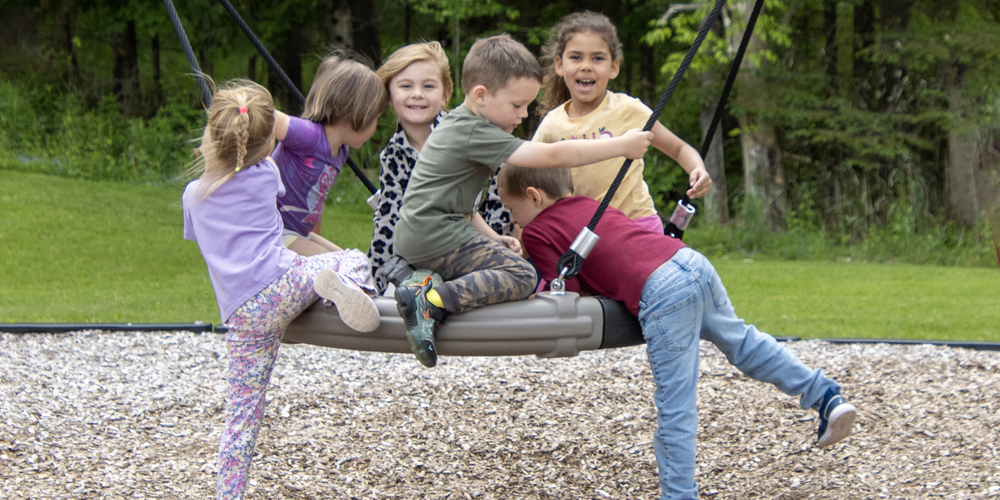 6 preschool children on a tire swing