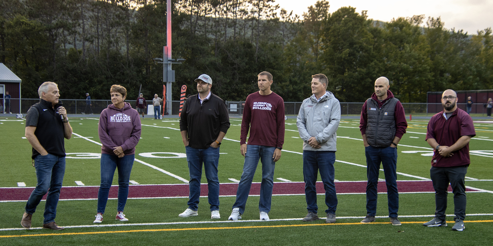 8 adults stand for recognition on the football field