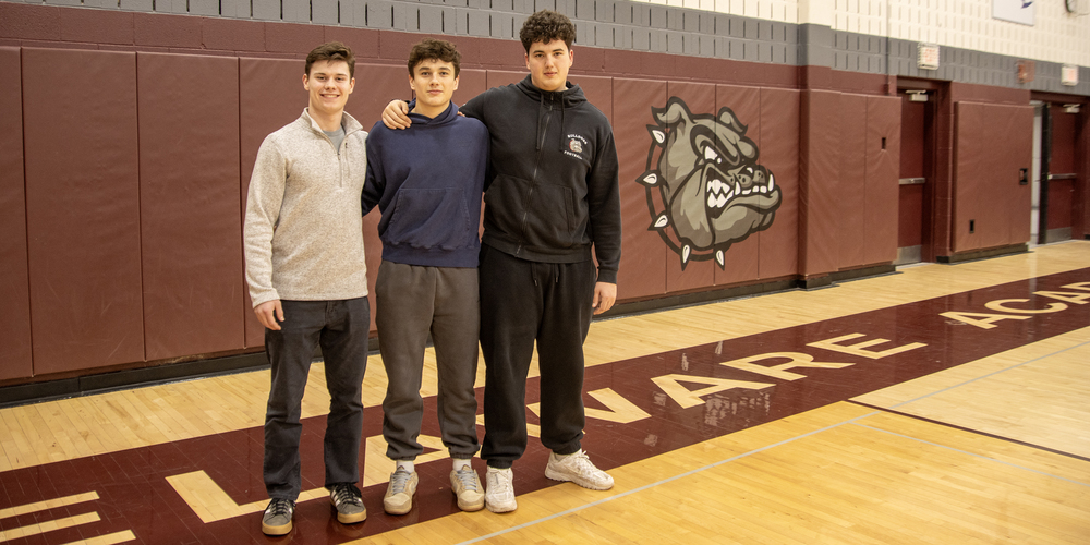 Adam Cook, Lucas Nealis and Steven Hillis pose in front of Bulldog logo
