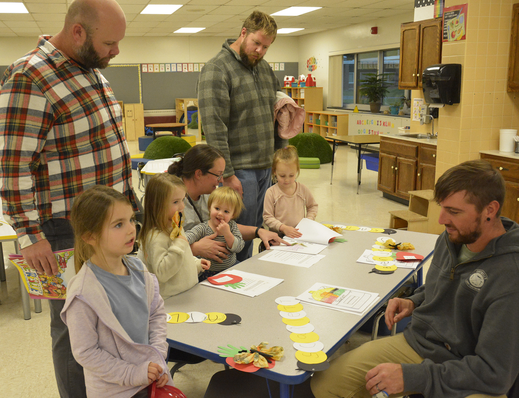 3 dads and a mom with children looing at paper on a table