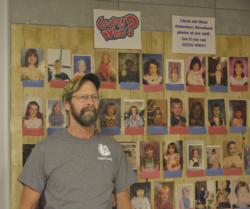 Man stands next to wall of photos