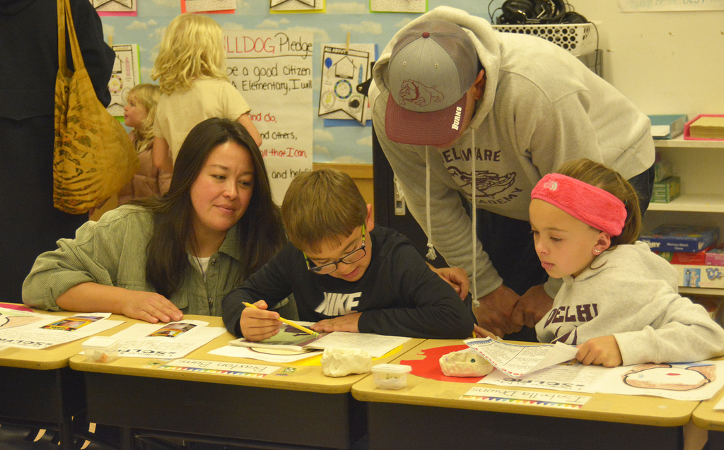 2 adults and two children at desks