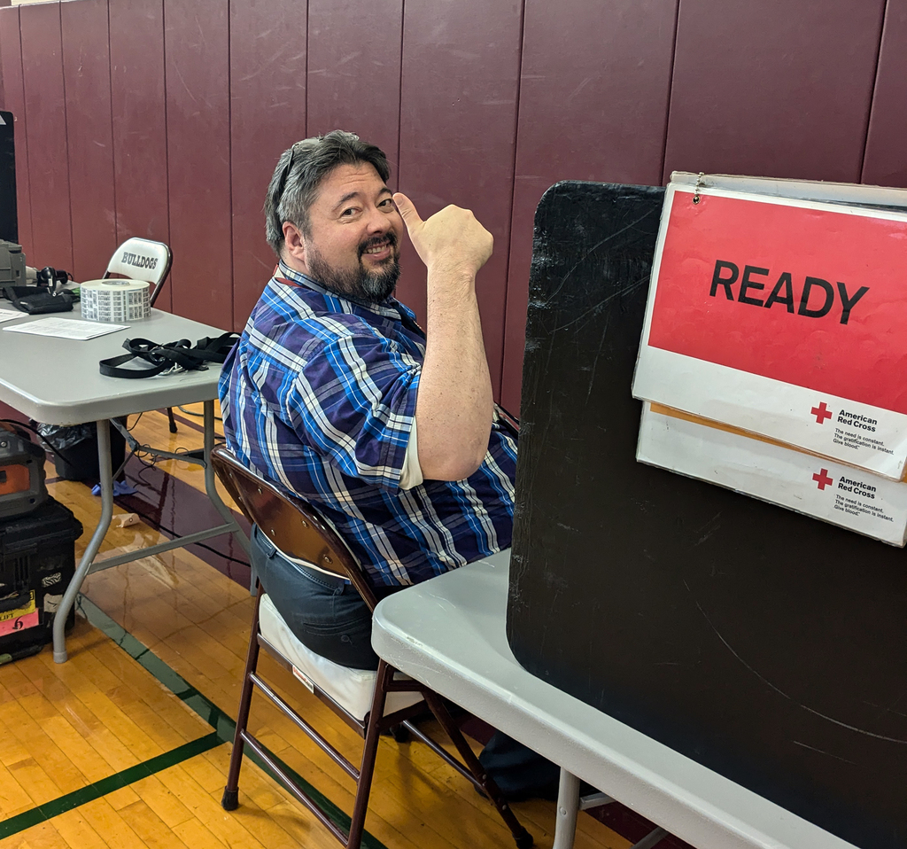 adult giving thumbs up sign as he sits at blood drive
