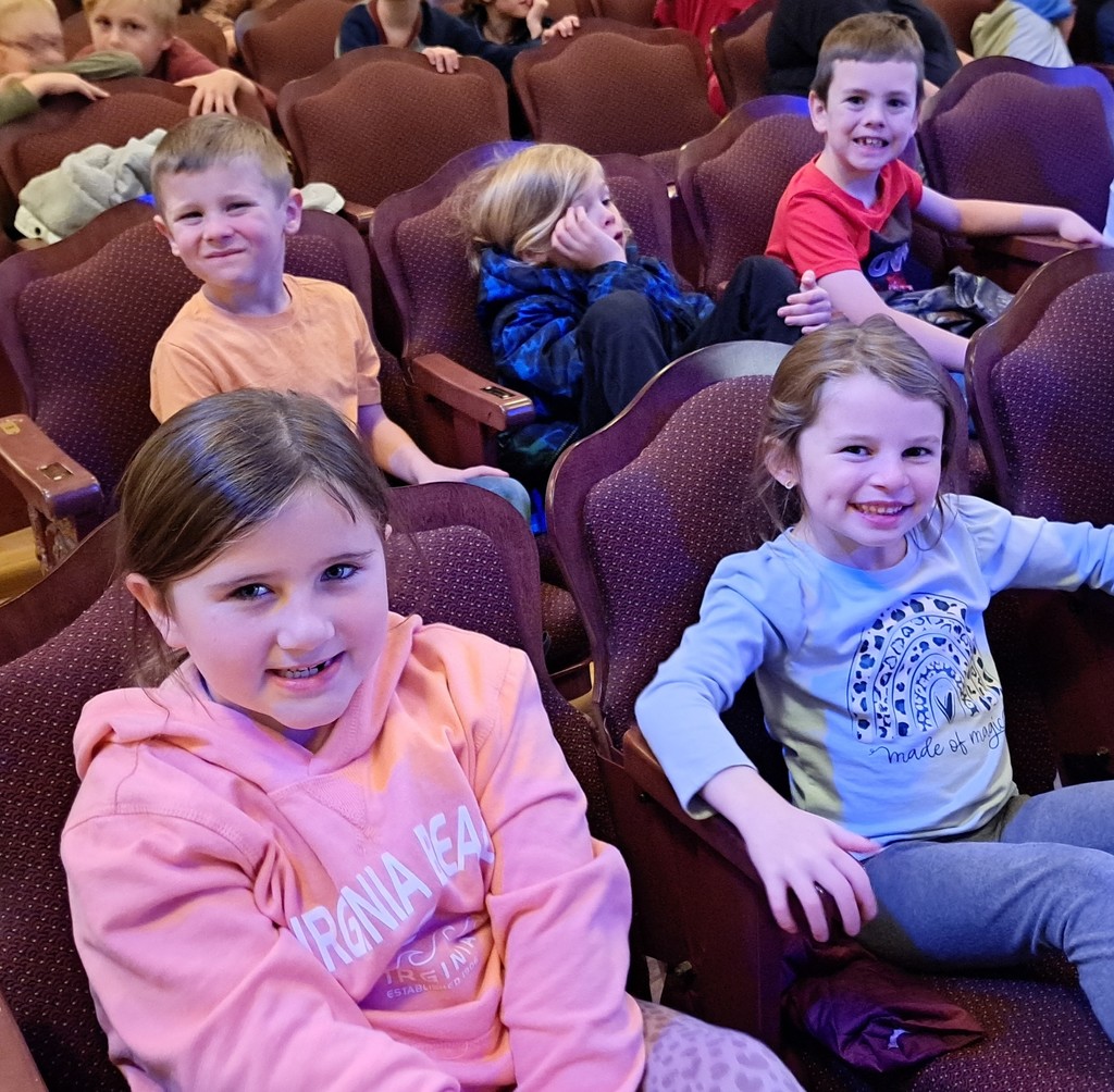 5 smiling elementary students in theater seats