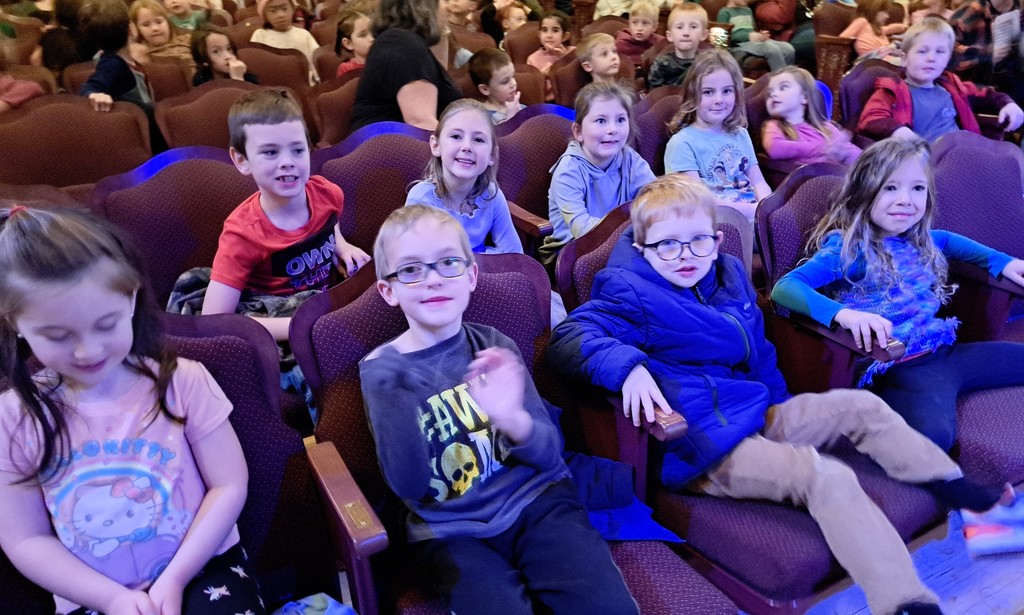 10 smiling elementary students in theater seats