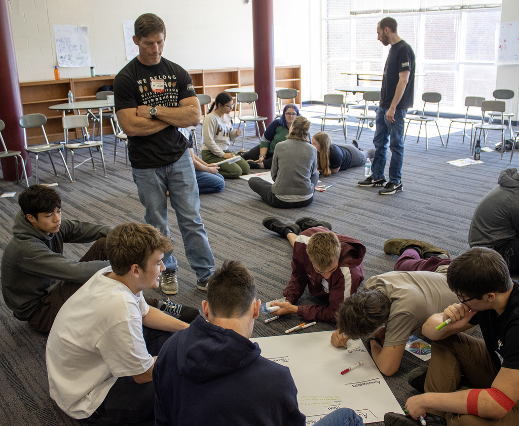 an adult looks over a student group's marker pad