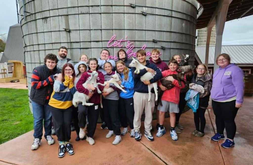 Mr. Broesler and the 8th grade PE class holding goats for a group picture