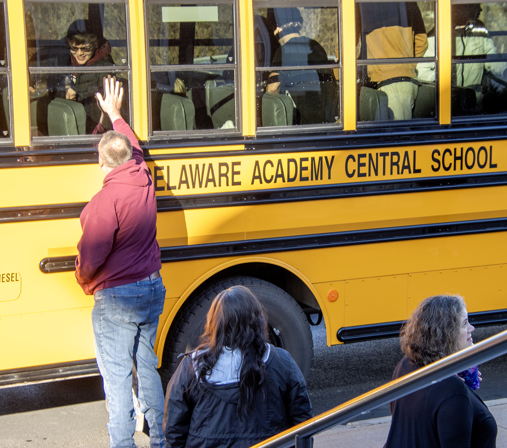 parent reaches up to a student on the bus