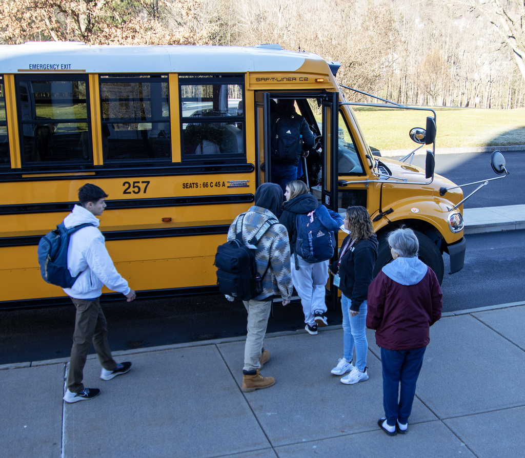 students board a bvus as two adults watch