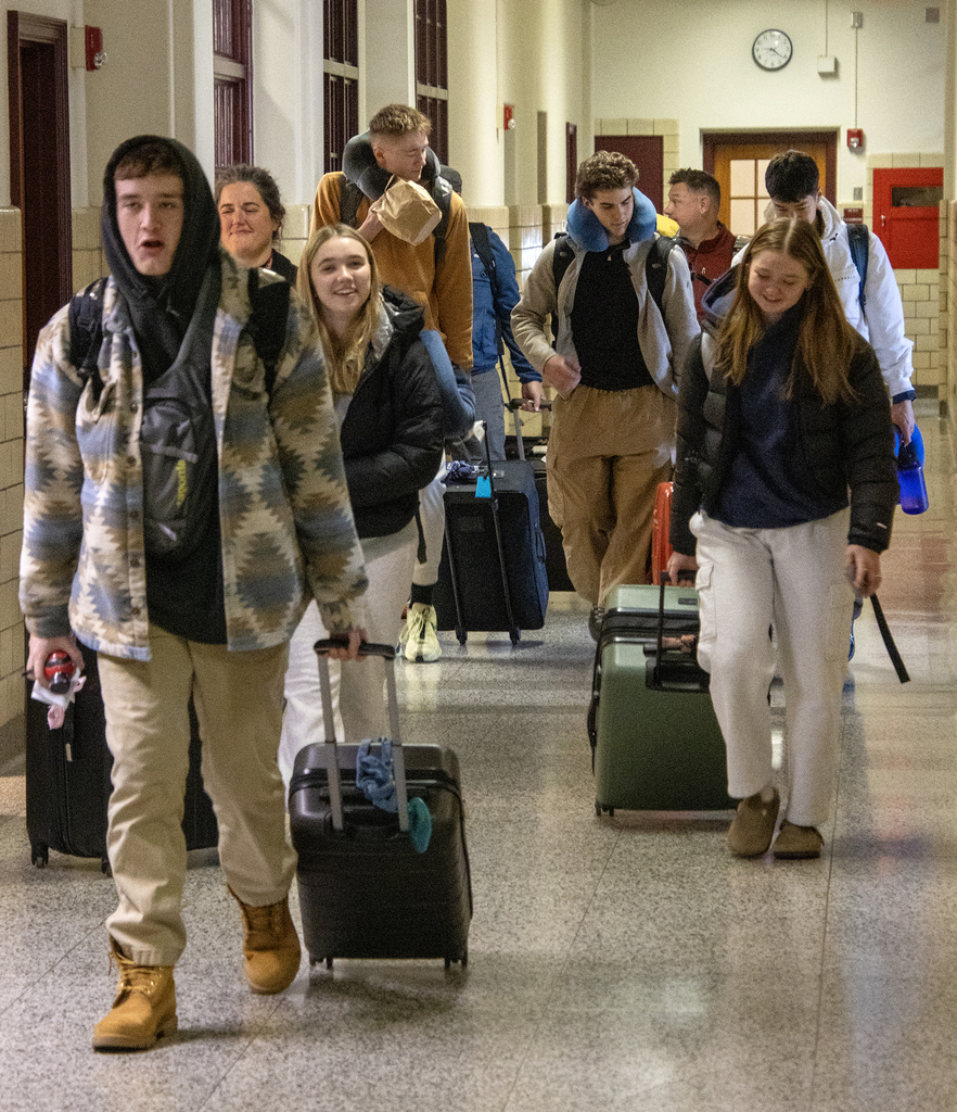 students in the hallway with suitcases