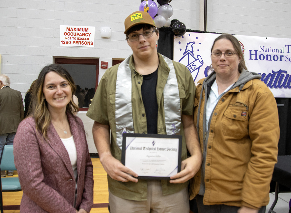 student poses with certificate, high school principal and his mother