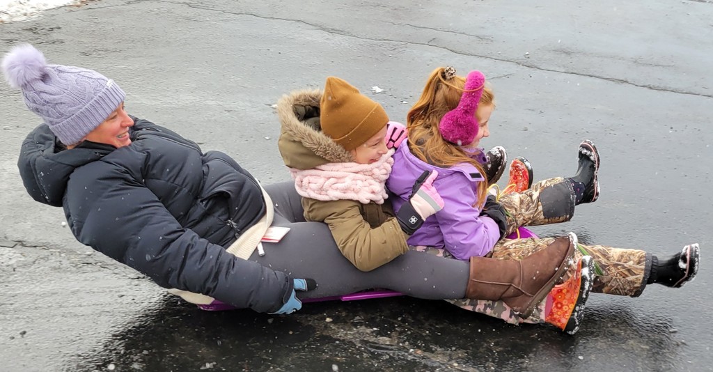 2 children and an adult sledding