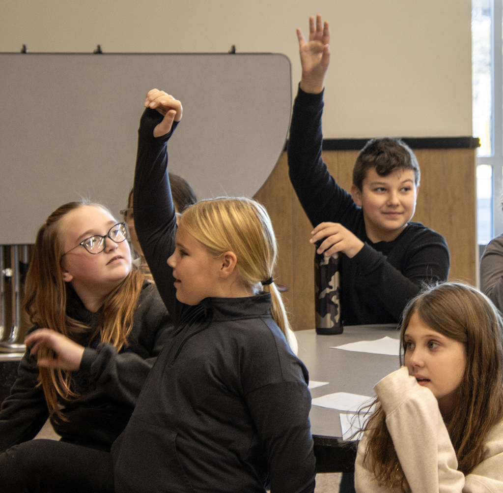 elementary students raise their hands