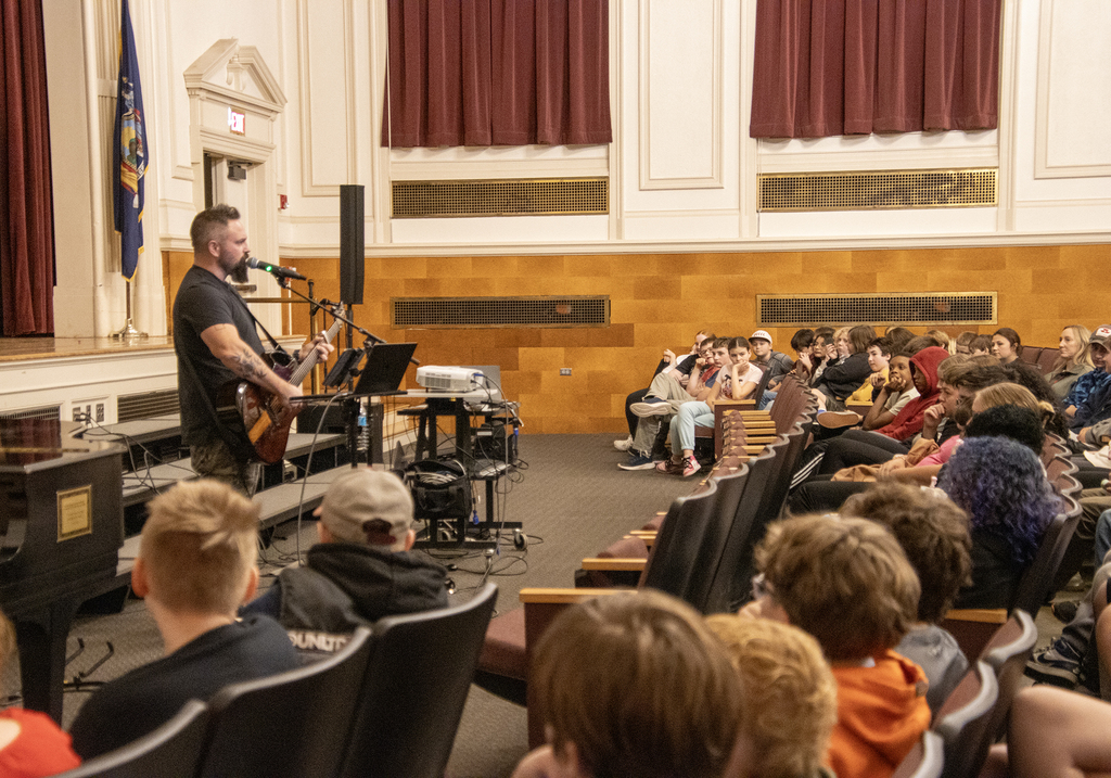 Singer with guitar in front of students