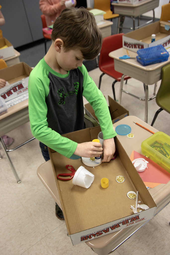 student poses with a leprechaun trap