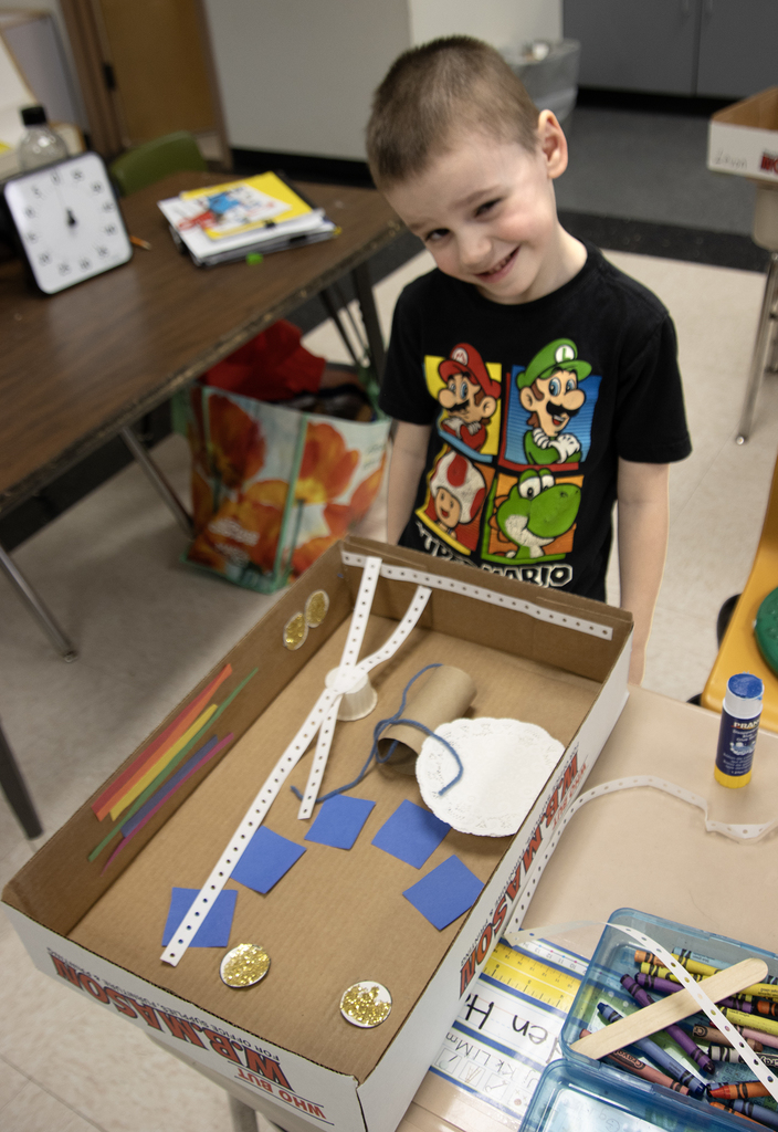 student poses with a leprechaun trap