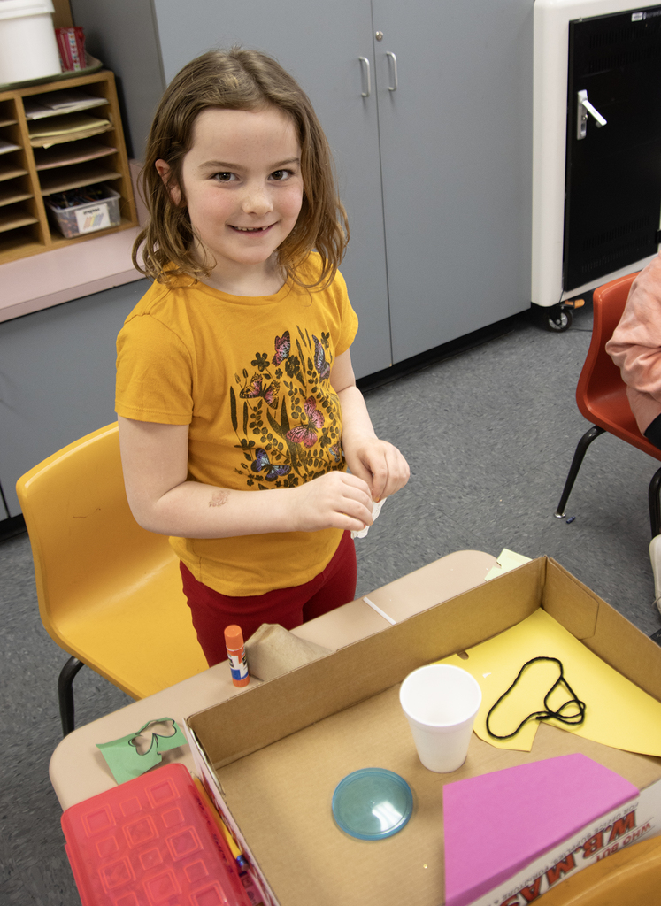 student poses with a leprechaun trap
