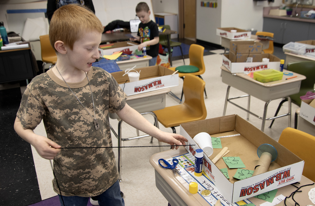 student poses with a leprechaun trap
