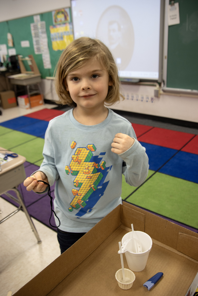student poses with a leprechaun trap