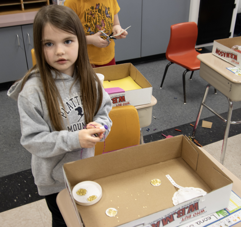 student poses with a leprechaun trap