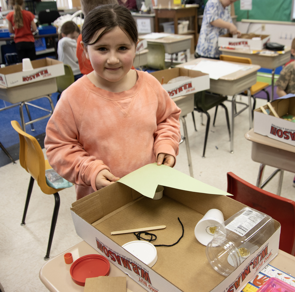 student poses with a leprechaun trap