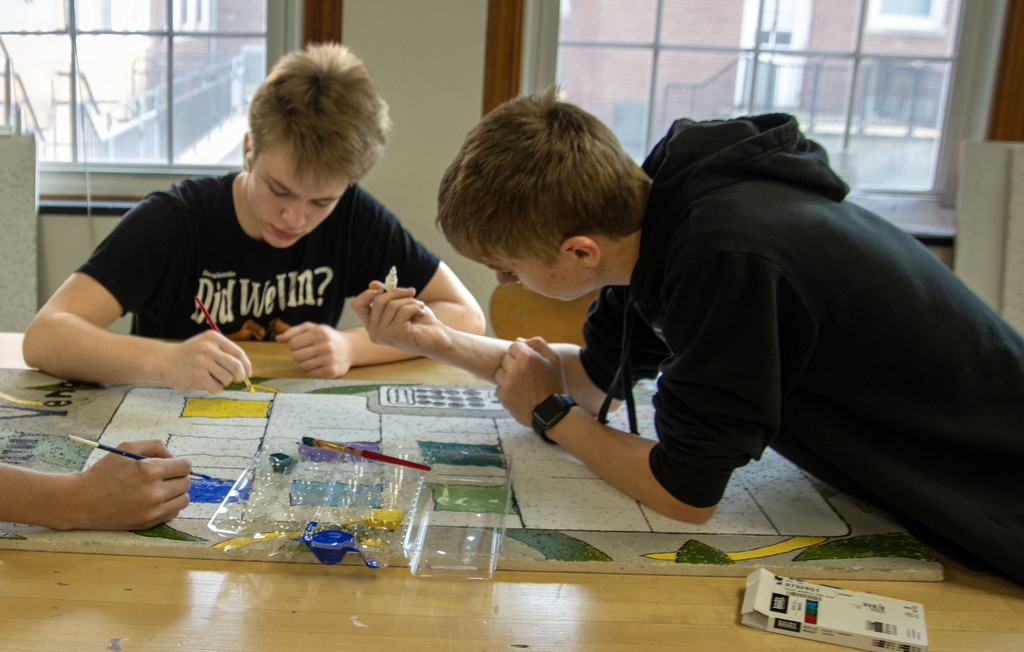 2 students work on pianting a ceiling tile