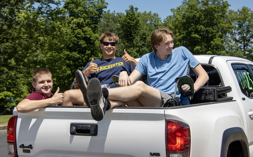 3 dudes giving thumbs up signs in the back of a truck