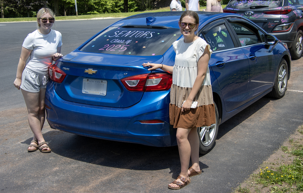 2 girls with their car, painted "Seniors Class of 2025"