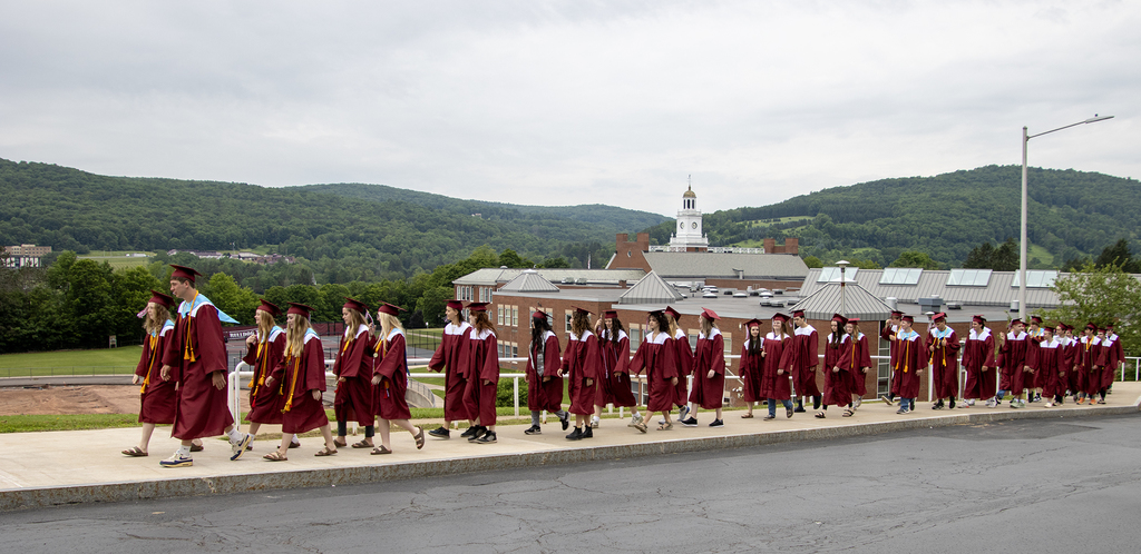 seniors walk up the hill with the school in the background