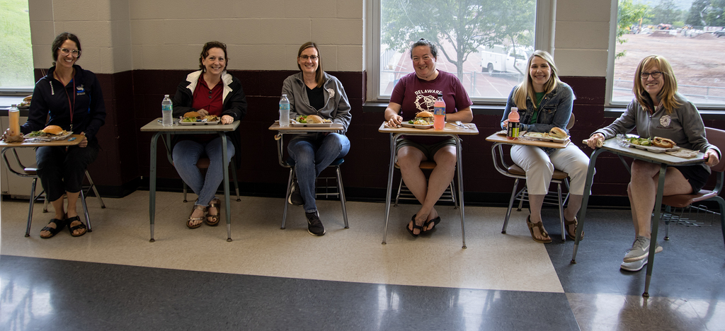 staff sit in school chairs at lunch