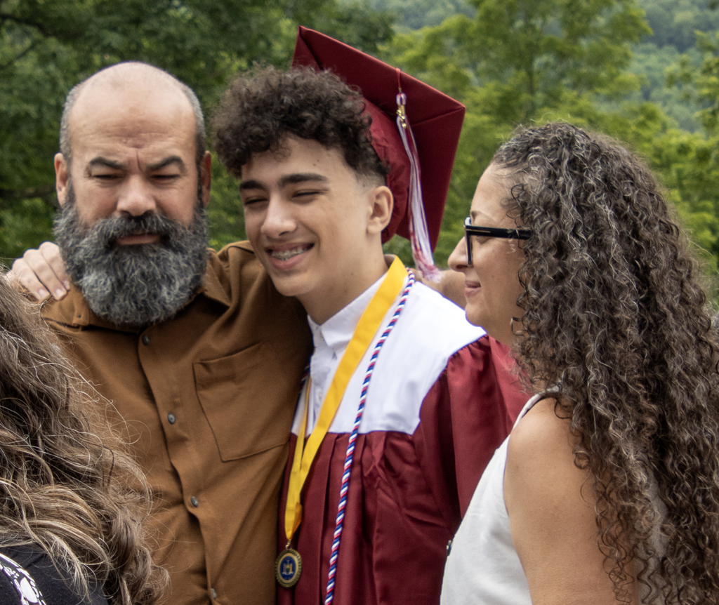 graduate and two adults hugging