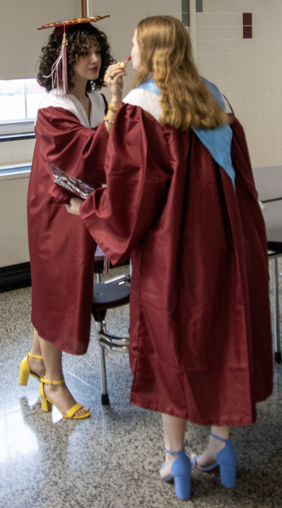 student helps another student with lipstick