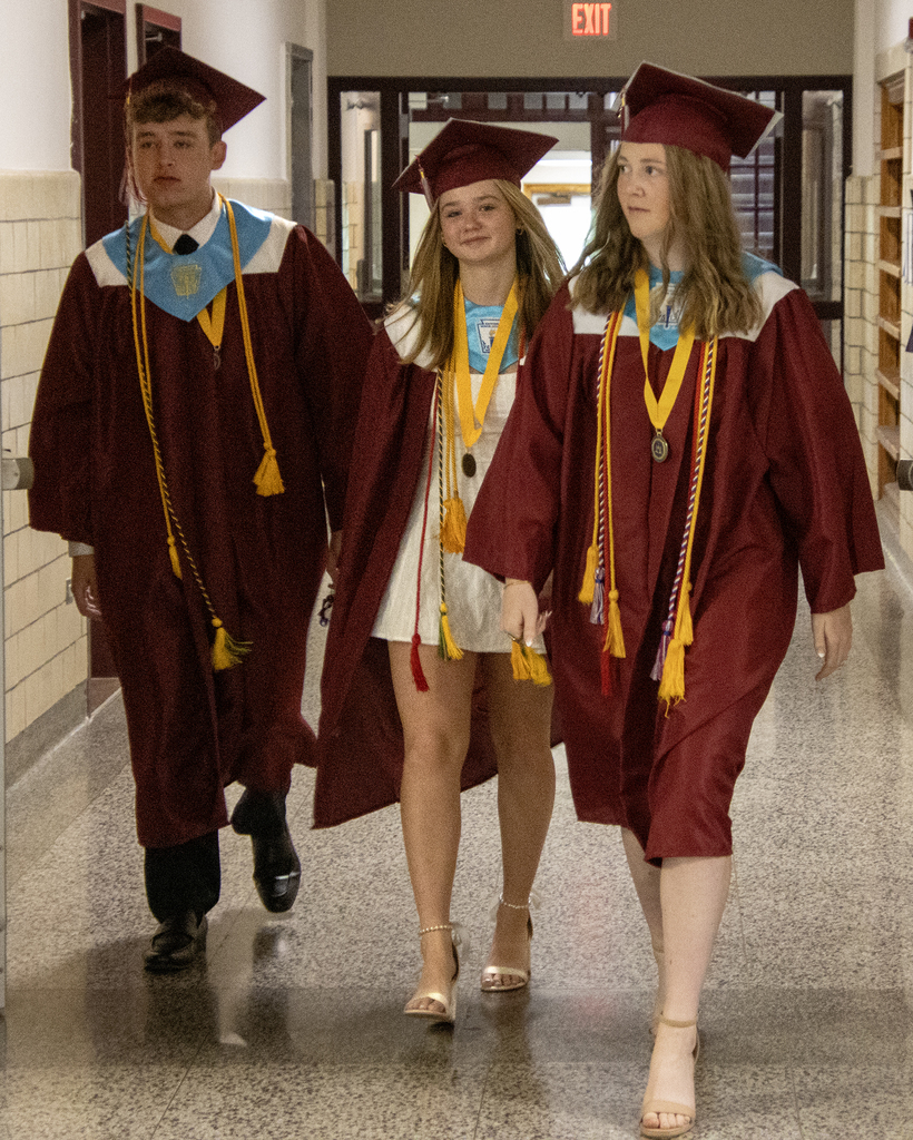 3 graduates walk down hall