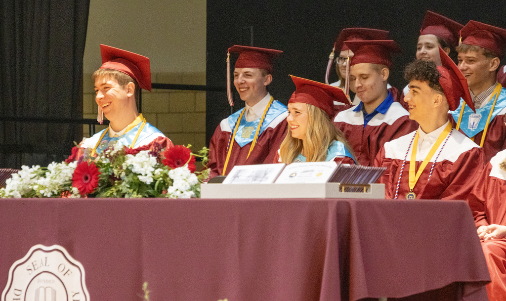graduating seniors laugh while on stage