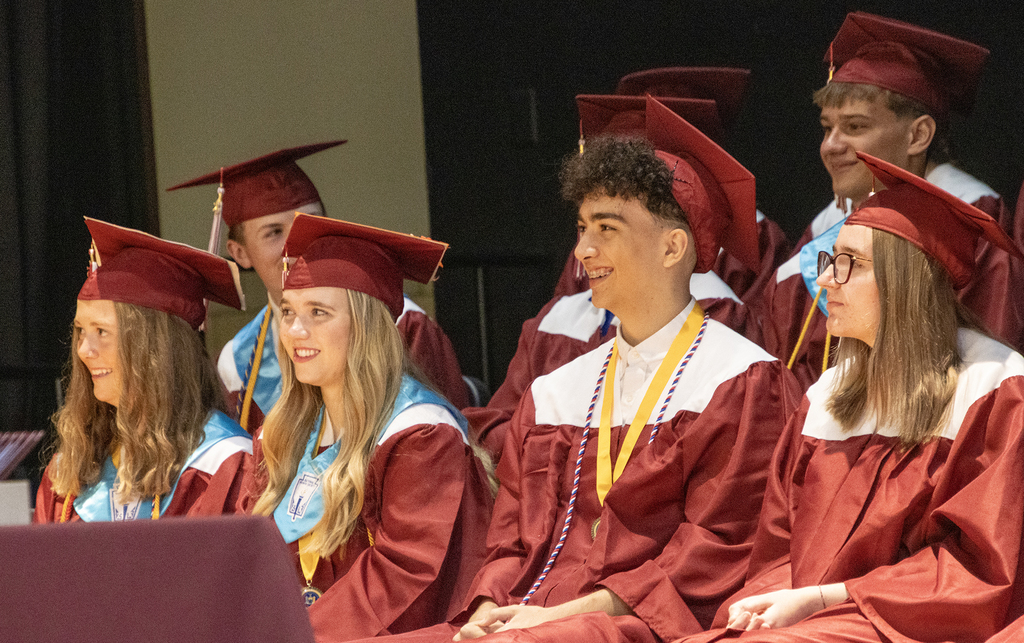 6 graduates smile on stage