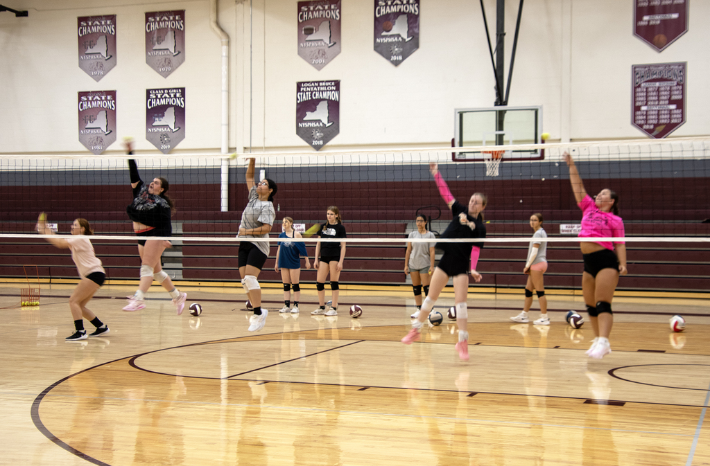 volleyball players leap into air at net