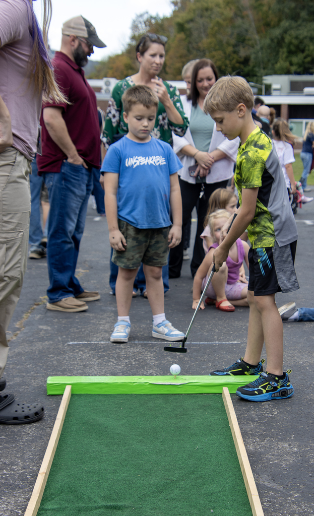 elementary student lines up a golf shot