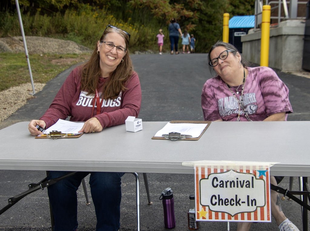 2 adult volunteers at carnival check-in table
